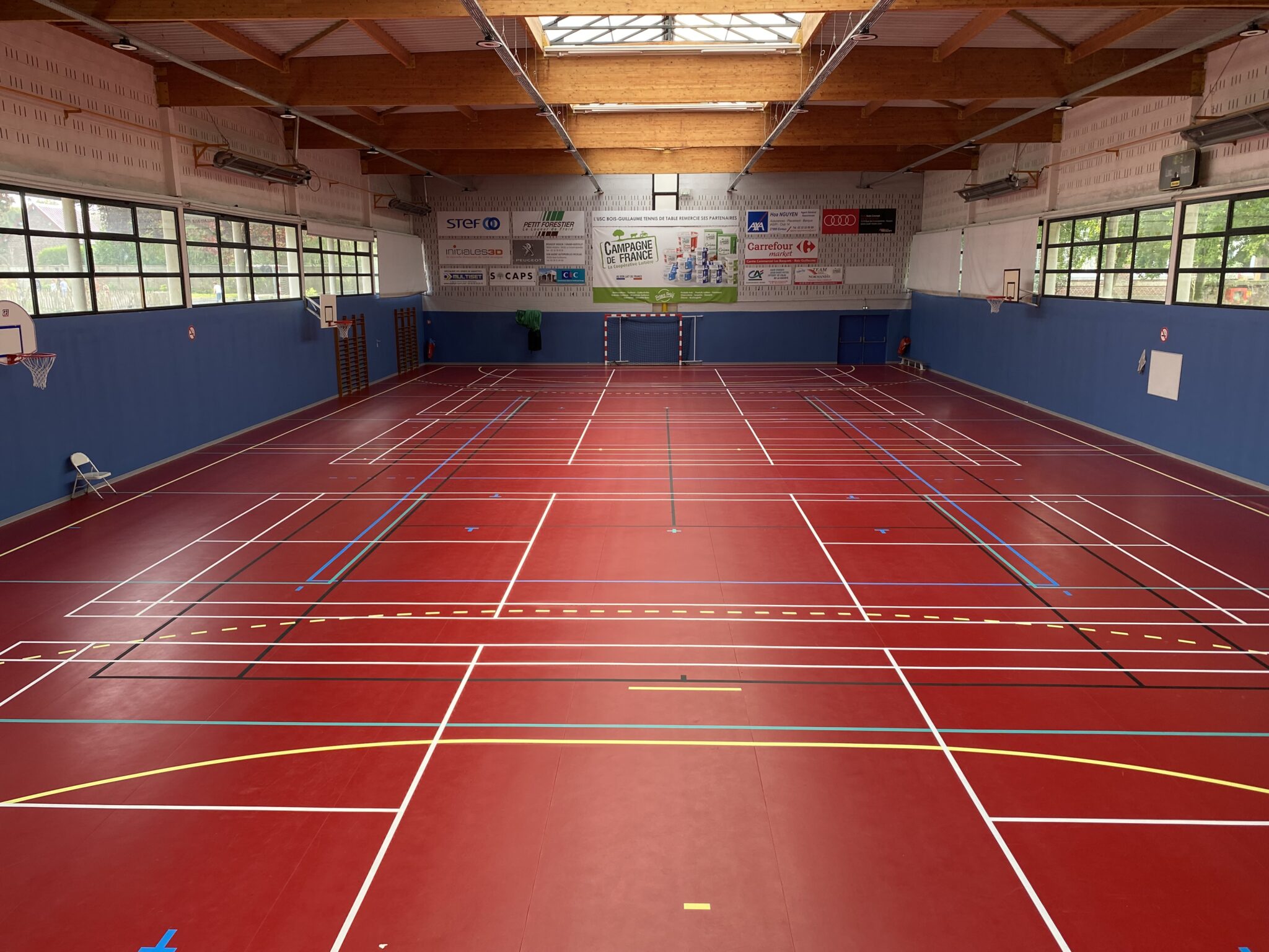 Gymnase intérieur multisports avec terrain de badminton.