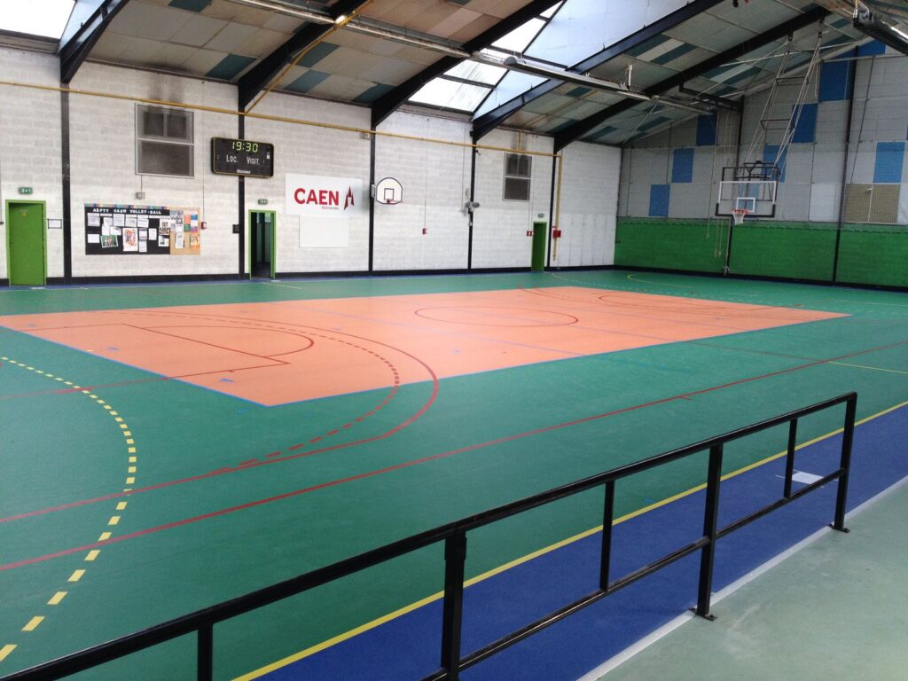 Gymnase intérieur vide avec terrain de basketball.